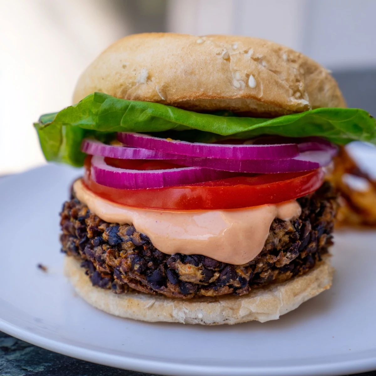 A delicious Vegan Black Bean Burger with smoky chipotle mayo, piled high on a toasted bun.