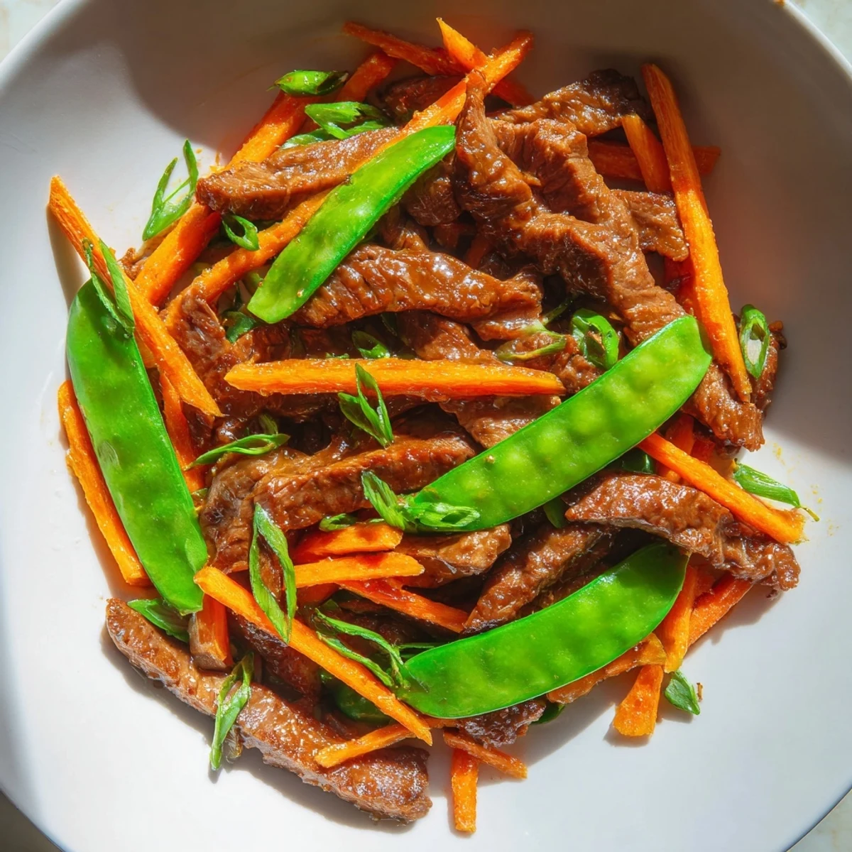 Sizzling beef stir fry with snow peas and carrots, a colorful weeknight meal served with rice.