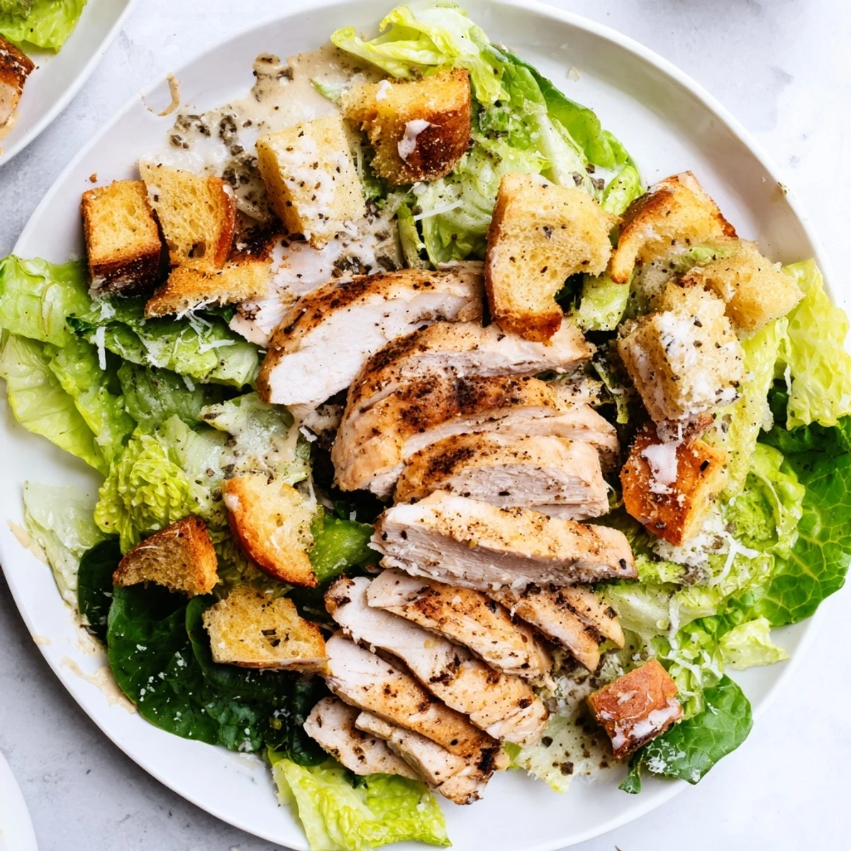 Freshly plated Chicken Caesar Salad with visible grilled chicken, crunchy croutons, and grated parmesan cheese.