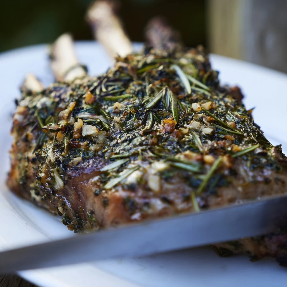 Herb Roasted Lamb Chops resting on a plate, garnished with fresh rosemary and served with lemon wedges.