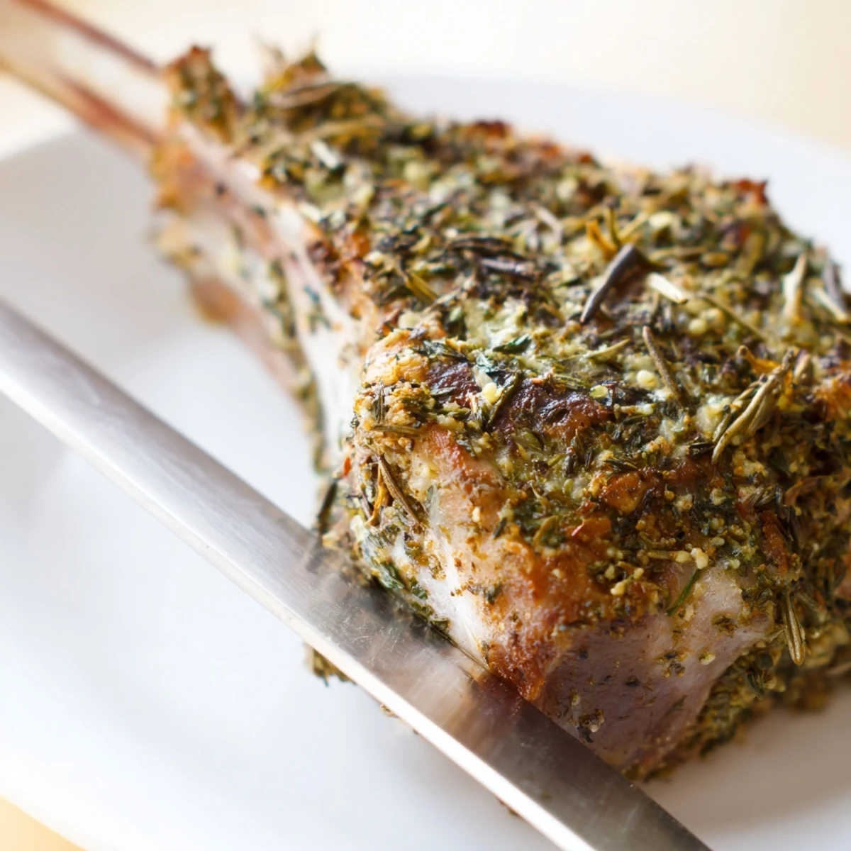 A close-up view of Herb Roasted Lamb Chops with a crispy herb crust and juicy pink interior.