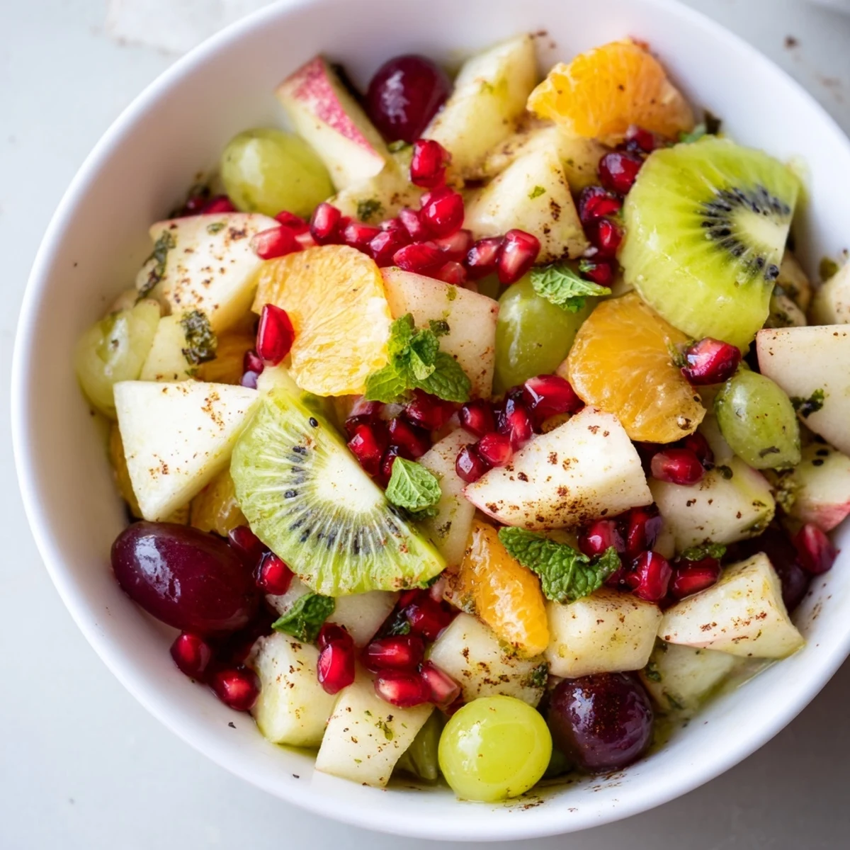 Overhead view of a vibrant Winter Fruit Salad with Honey Lime Dressing, mixing colorful kiwi slices and dried cranberries in a large glass bowl with zesty dressing.