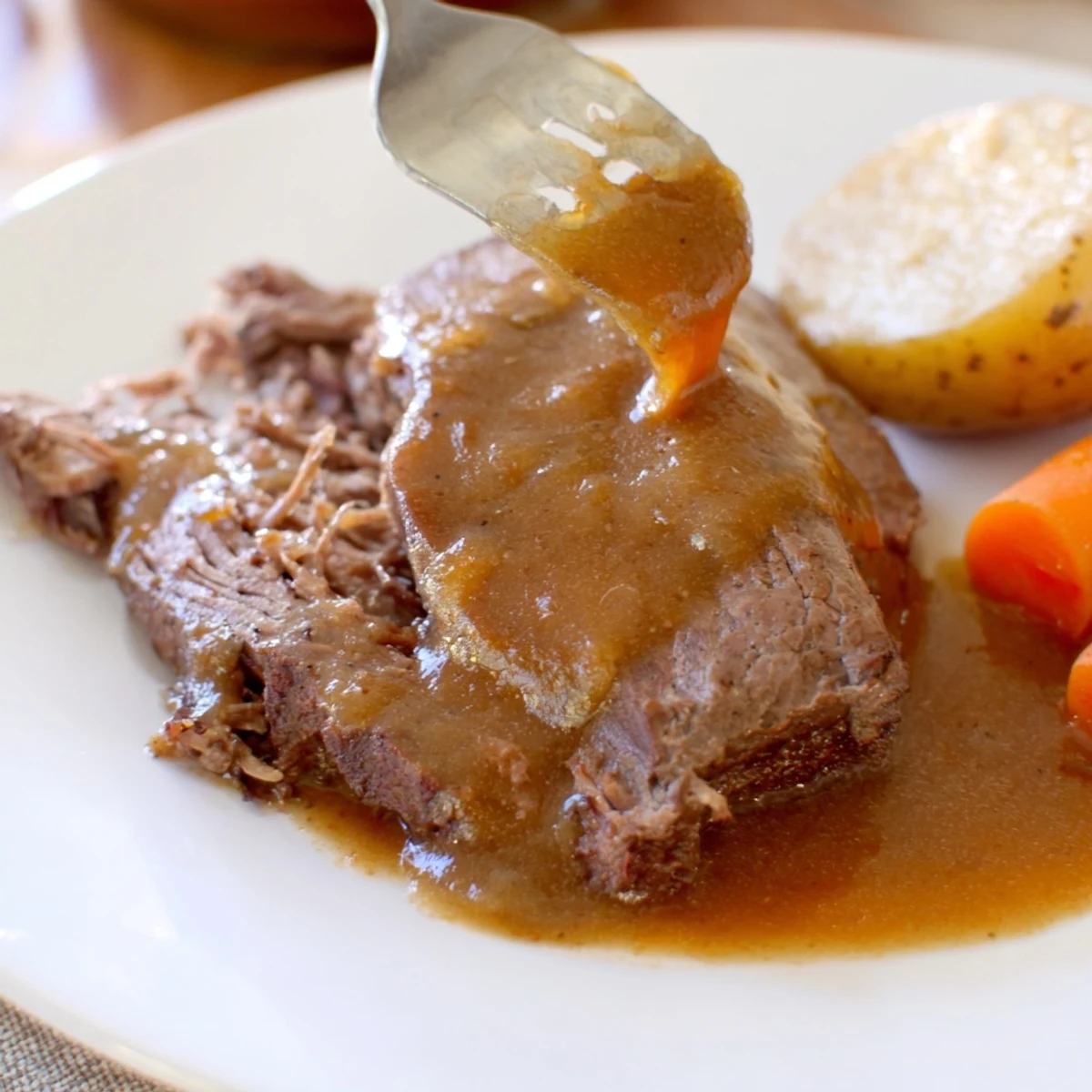 Savory Slow Cooker Pot Roast with Gravy spooned over tender vegetables and beef.