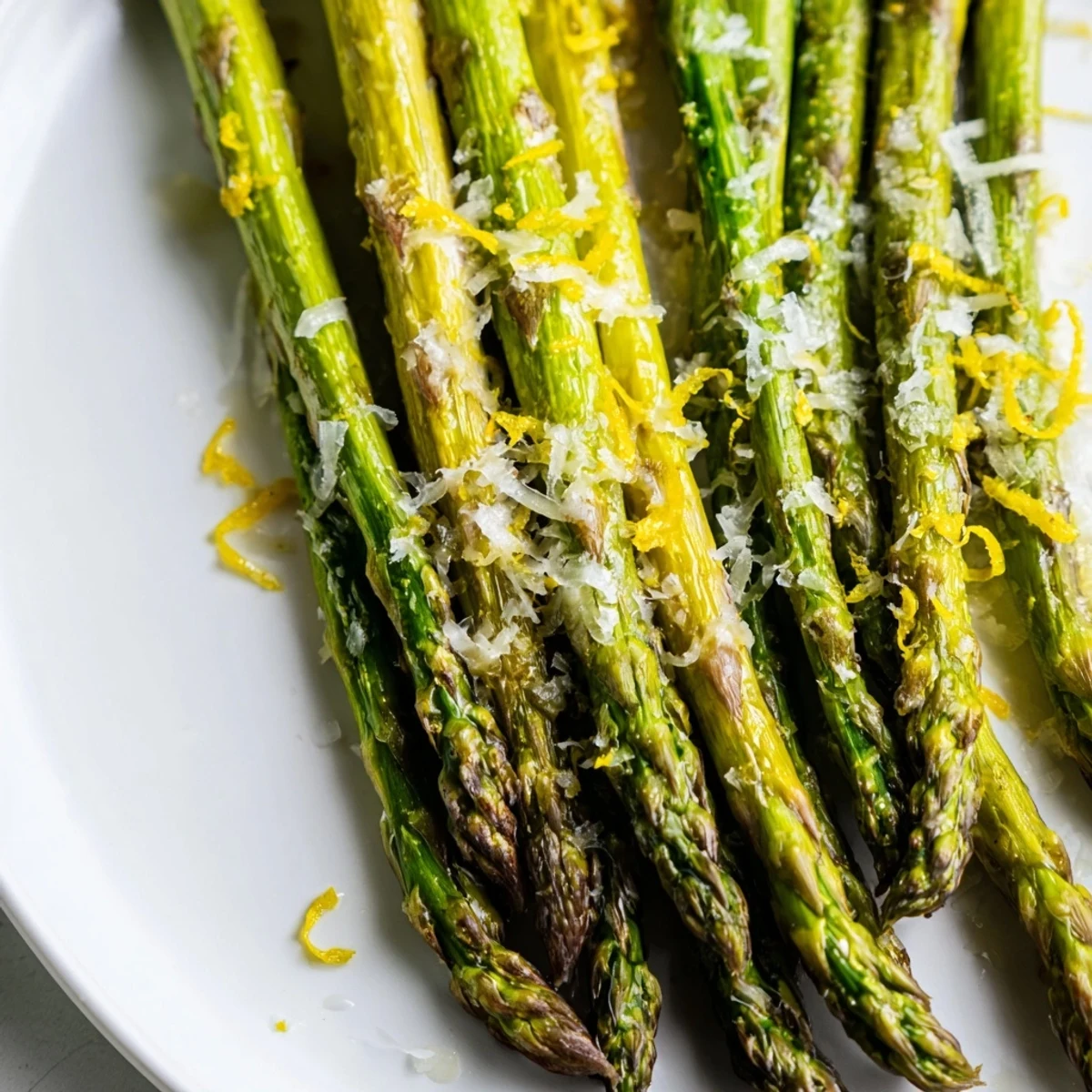 Tender roasted asparagus with Parmesan and lemon, garnished with lemon wedges for a zesty Mediterranean side dish.