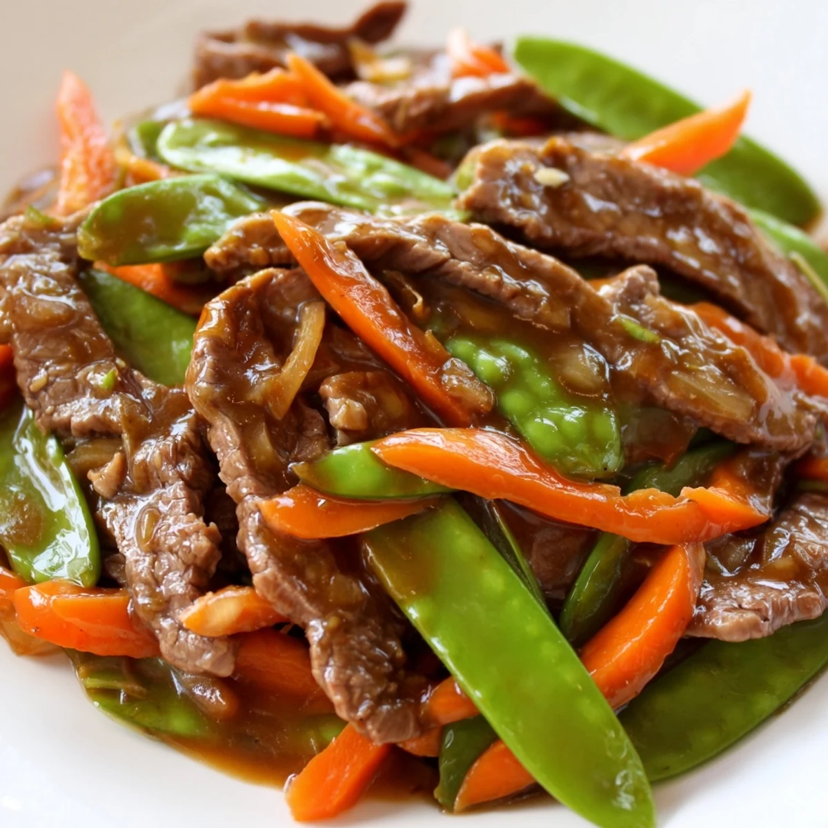 Fork-tender beef strips and vibrant crisp snow peas and carrots glisten in savory stir fry sauce.