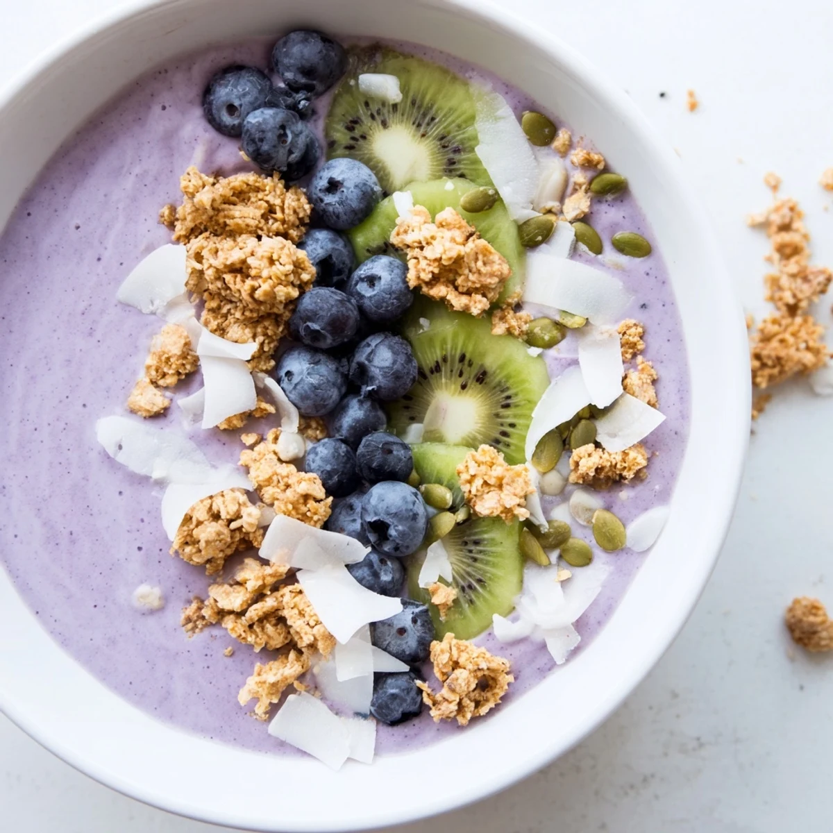 Served for breakfast, the Winter Berry Smoothie Bowl is garnished with coconut flakes and pumpkin seeds for texture.