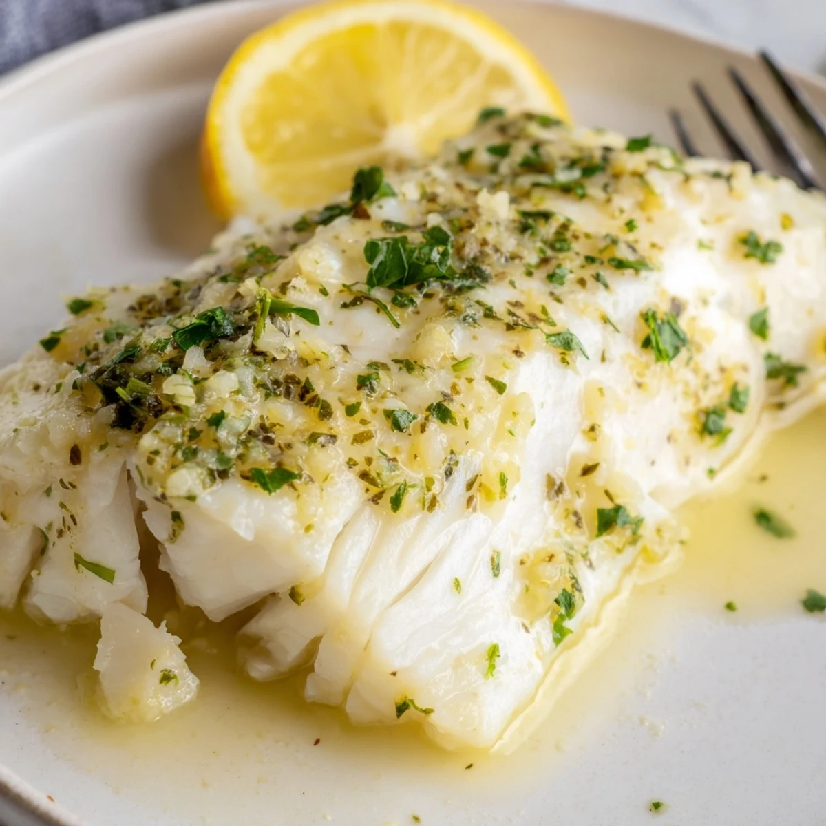 Tender fillets of Baked Halibut with Lemon Butter, glistening with a zesty garlic sauce in a ceramic baking dish.