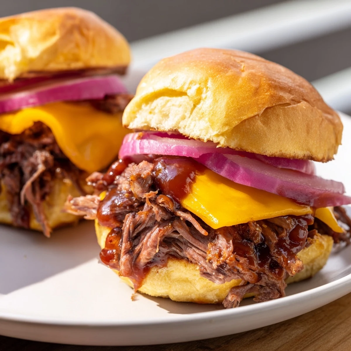 Tender slow-cooked beef brisket sliders with melted cheddar and red onions on soft buns, ready to serve.