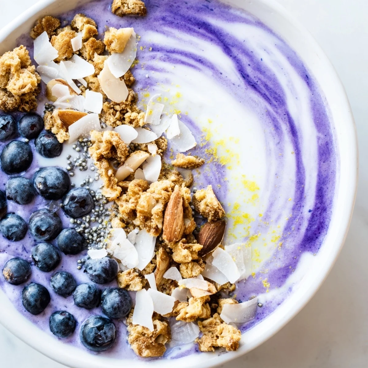 A spoonful of vibrant purple smoothie bowl with lemon zest, showing the thick texture and colorful toppings.