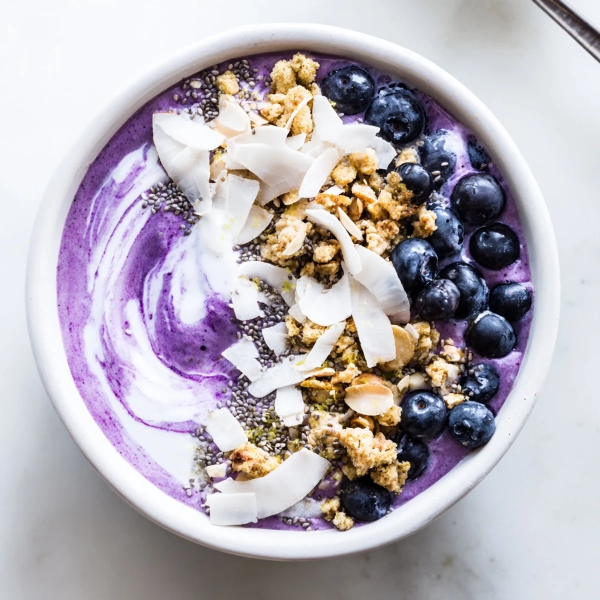 Healthy Lemon Blueberry Smoothie Bowl served in a white bowl, garnished with coconut flakes and chia seeds.