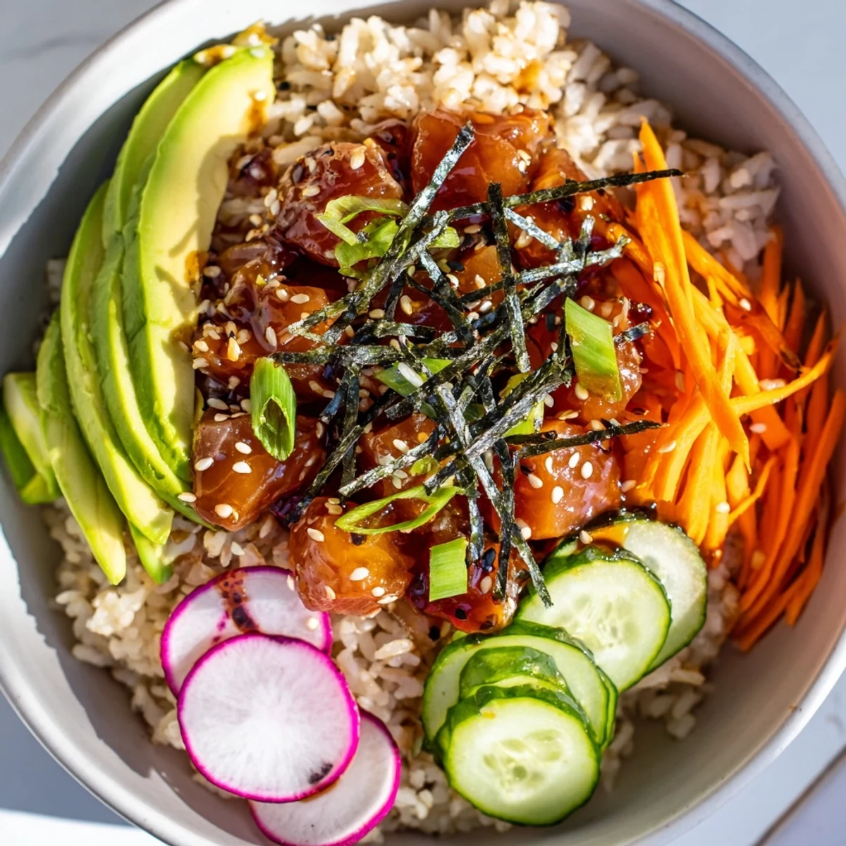 A close-up of a spicy tuna poke bowl with avocado slices, colorful veggies, and sesame seeds over seasoned rice.