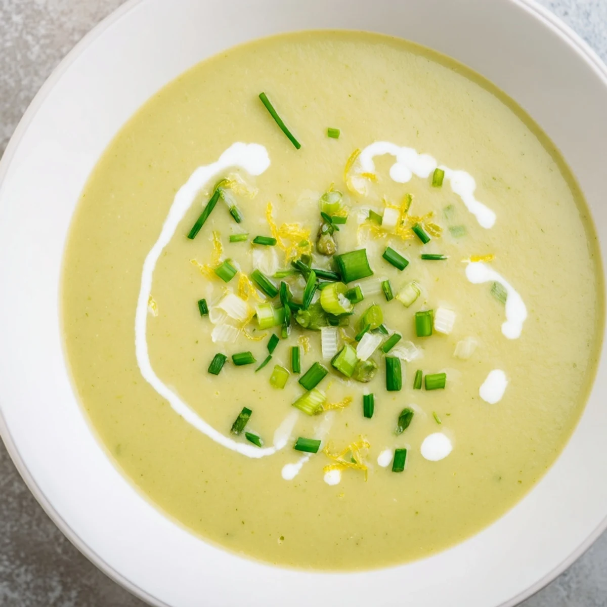 Steaming bowl of Creamy Asparagus Soup with Lemon garnished with fresh chives.