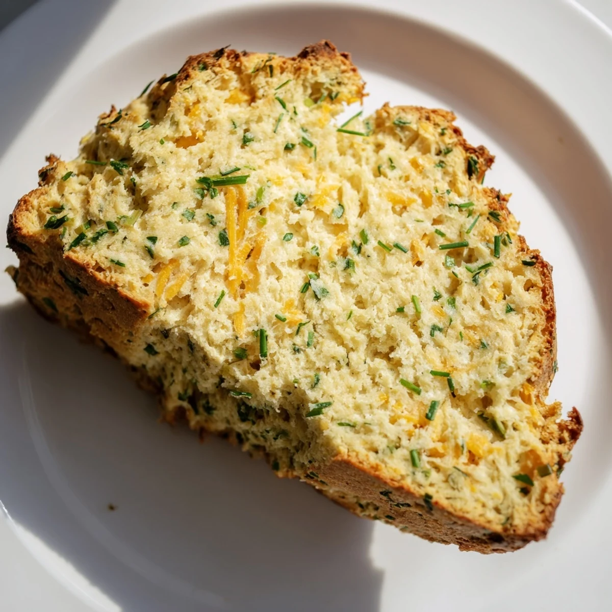 Savory Herbed Cheddar Irish Soda Bread served warm with a pat of butter alongside a steaming bowl of soup.
