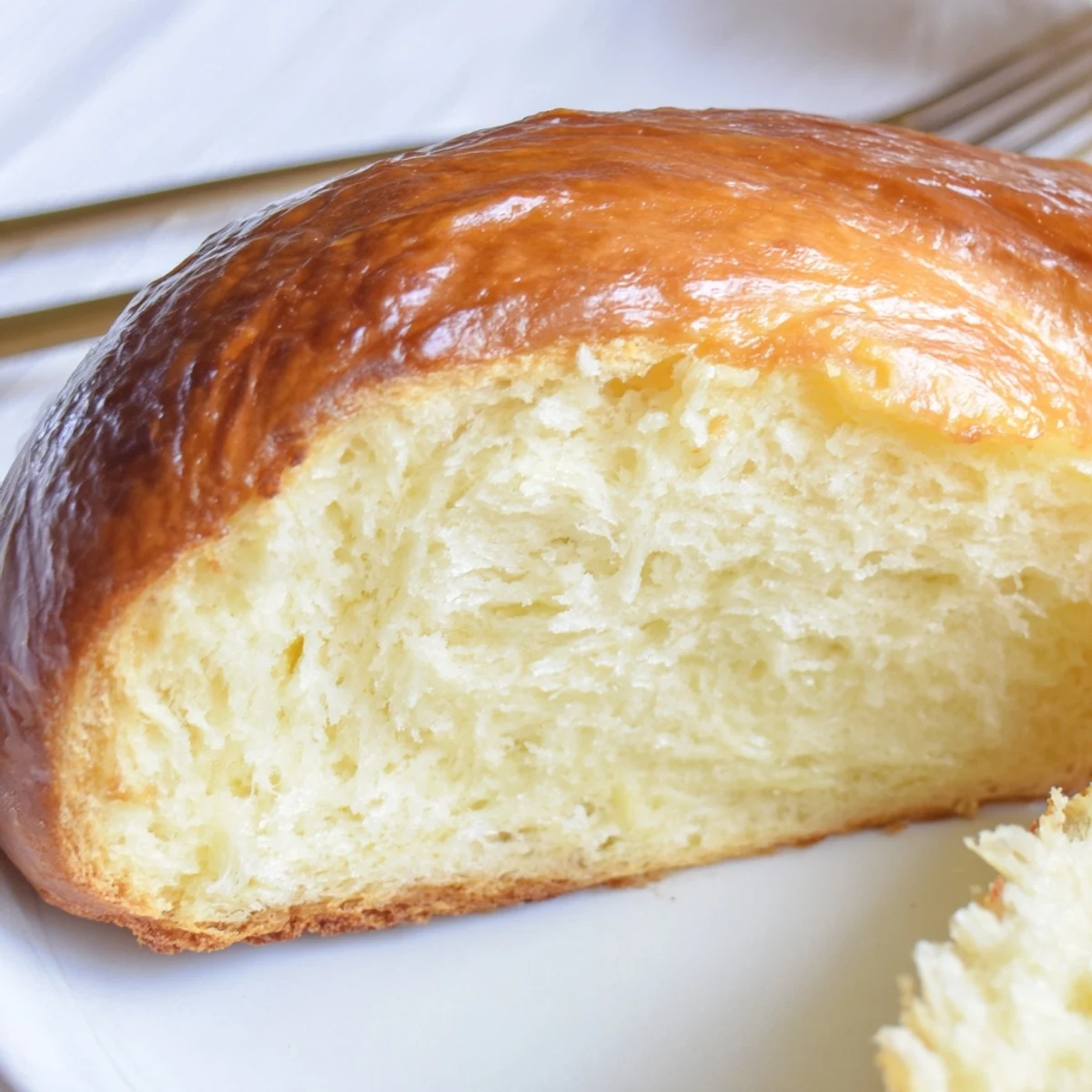 A freshly baked Milk Brioche loaf rests on a wire rack, showcasing its golden, buttery crust and soft, pillowy interior perfect for breakfast toast.
