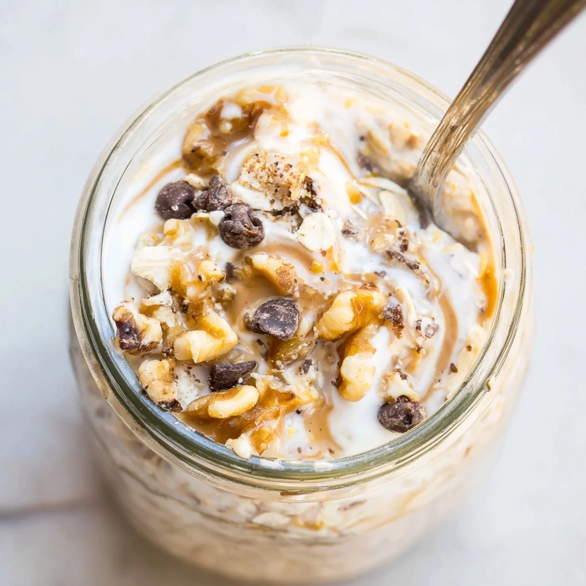 Thick and indulgent cookie dough overnight oats with swirls of nut butter and a sprinkle of cinnamon for morning cravings.