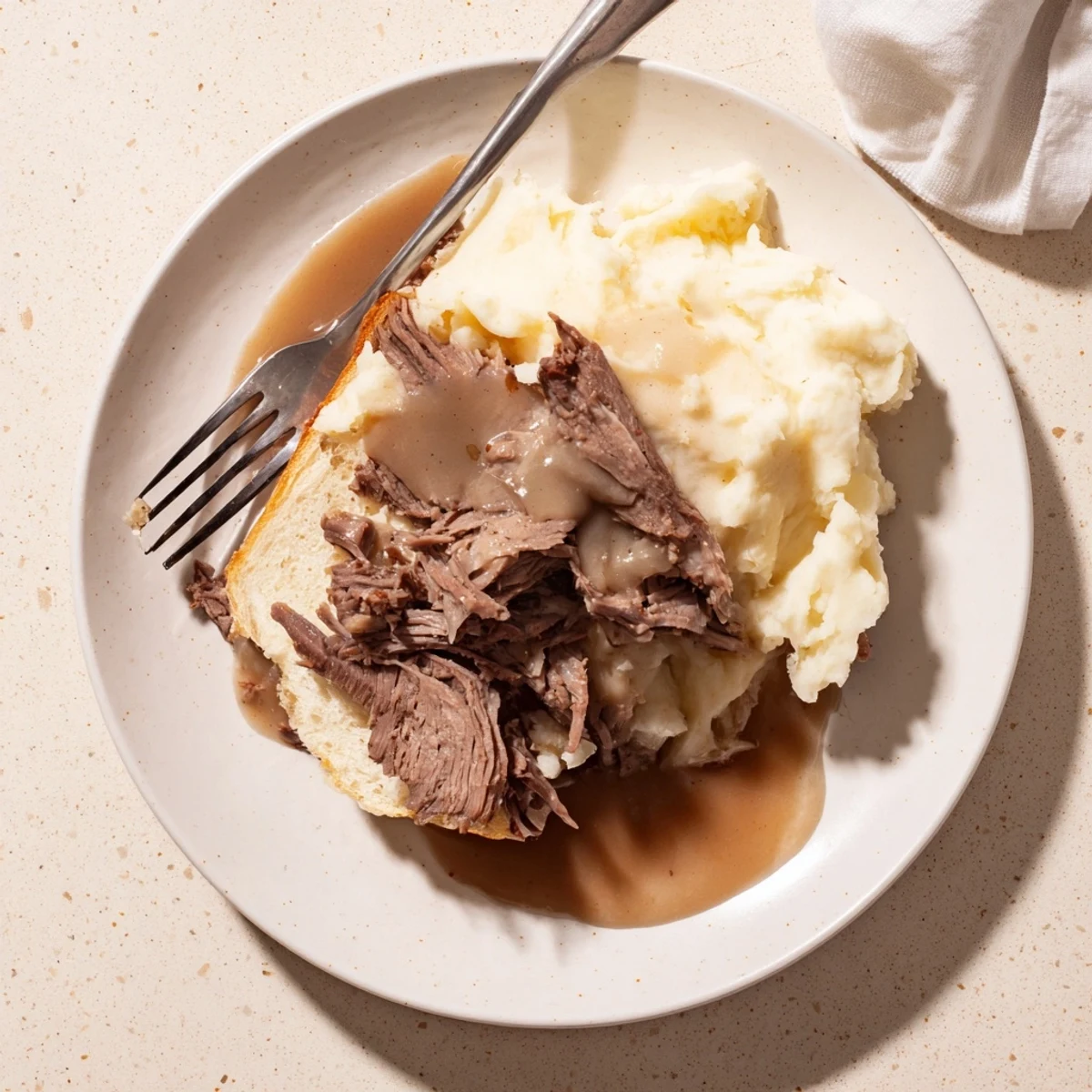 Hearty Midwestern Slow Cooker Beef Manhattan served hot with savory shredded beef, smooth mashed potatoes, and onions in rich brown gravy.