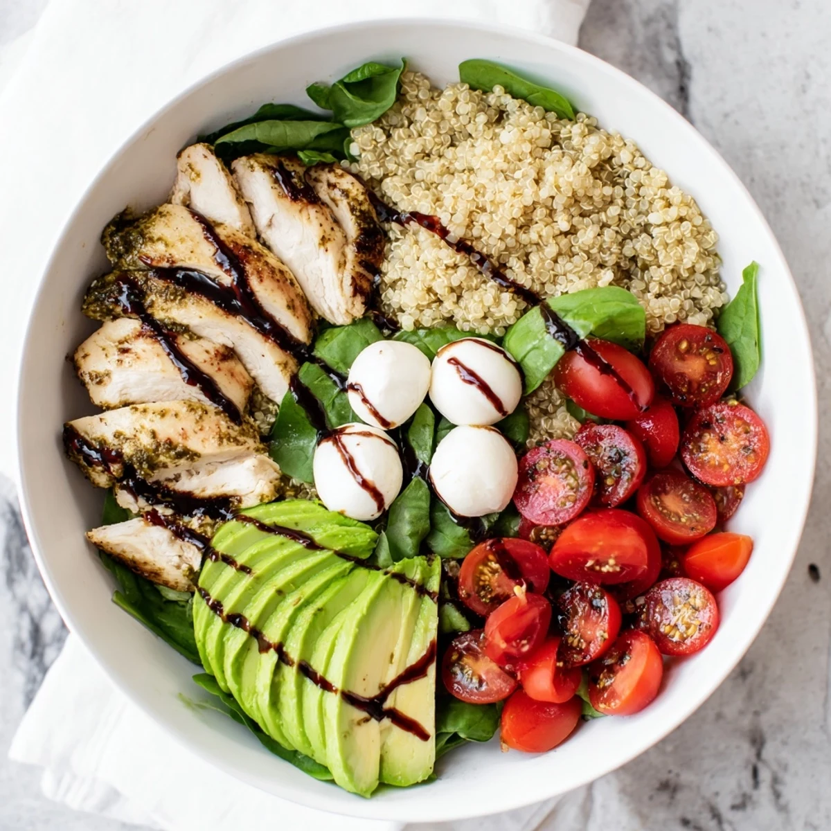 A wholesome Pesto Chicken Caprese Grain Bowl serves tender pesto chicken, cherry tomatoes, and mozzarella balls with arugula.