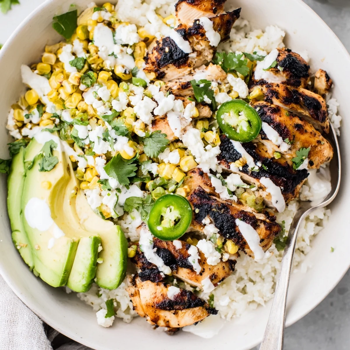 Grilled chicken slices topped with charred corn and crema for a Street Corn Chicken Bowl.  