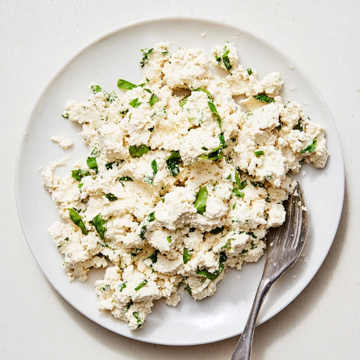 A creamy bowl of Tofu Ricotta garnished with fresh basil, ready for vegan lasagna or stuffed shells.