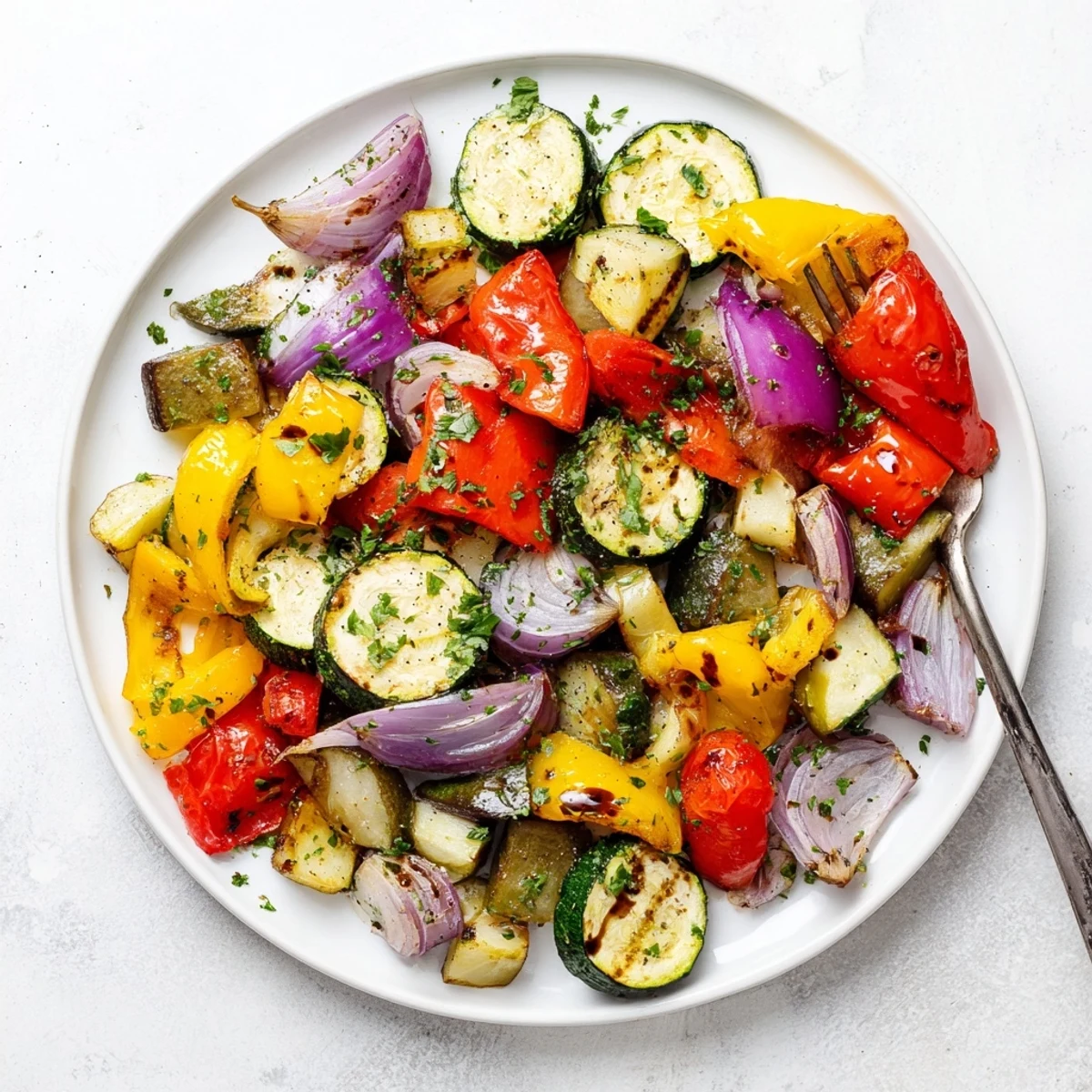 A close-up of Italian Roasted Vegetables sizzling with olive oil and herbs, perfect served alongside grilled chicken or pasta.