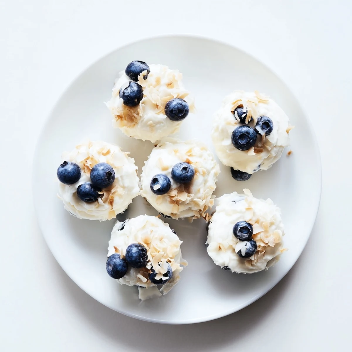 Fresh blueberry Greek yogurt bites arranged on a parchment-lined baking sheet with plump berries nestled into creamy frozen mounds