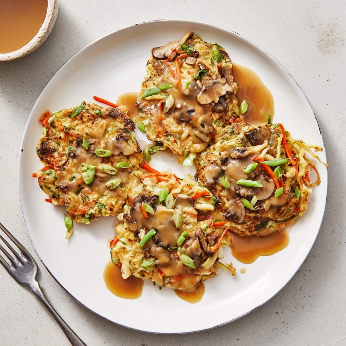 Homemade Egg Foo Young with bean sprouts and meat in rich sauce garnished with green onions