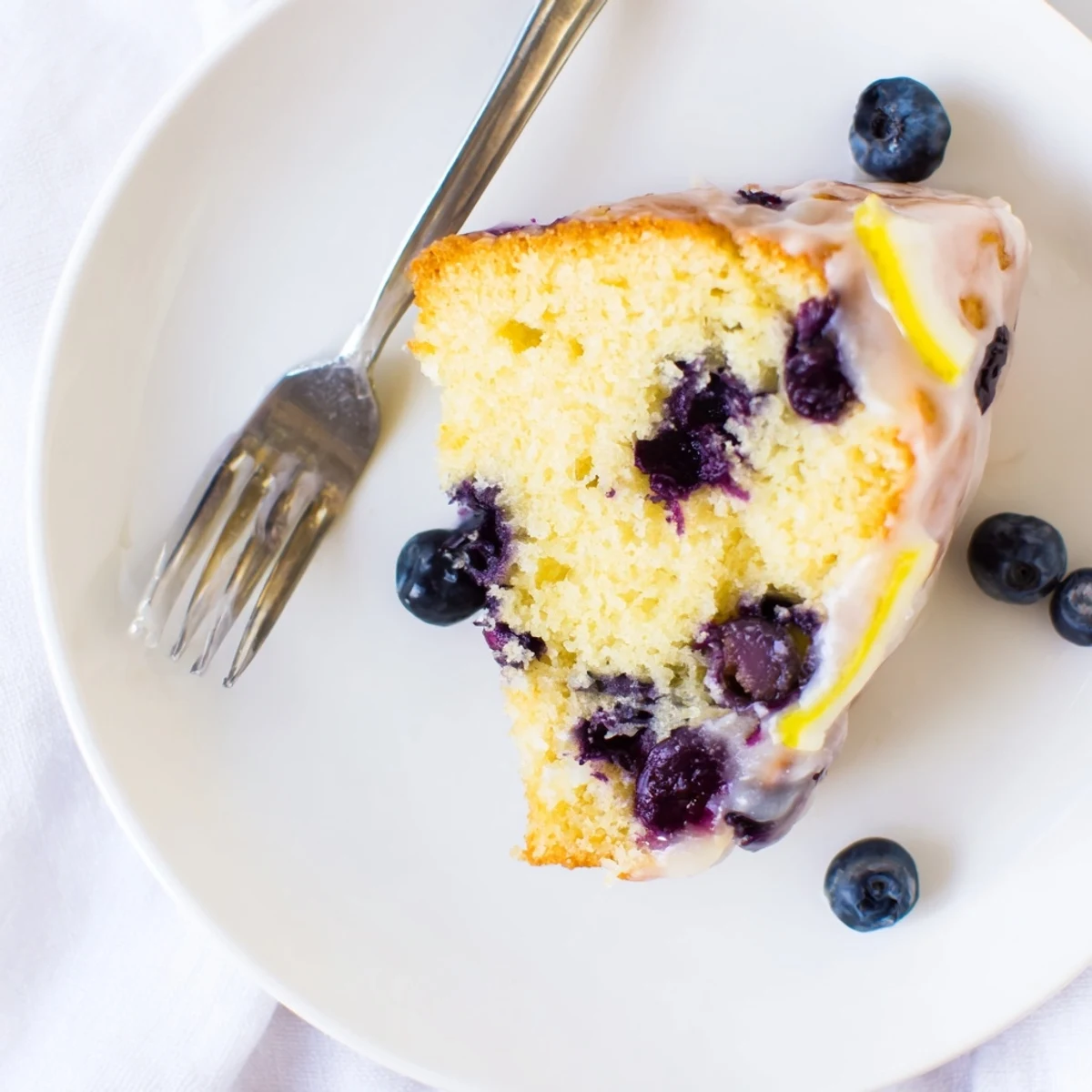 Moist lemon blueberry cake drizzled with tangy glaze and topped with fresh blueberries