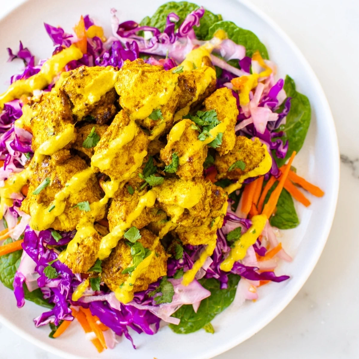 Fusion curried chicken lime coleslaw plated with refreshing mint yogurt sauce and fresh cilantro garnish