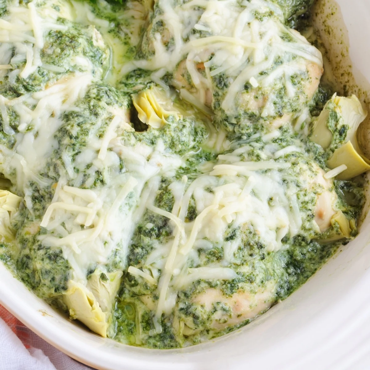 Creamy baked pesto spinach artichoke chicken fresh from the oven with gooey cheese