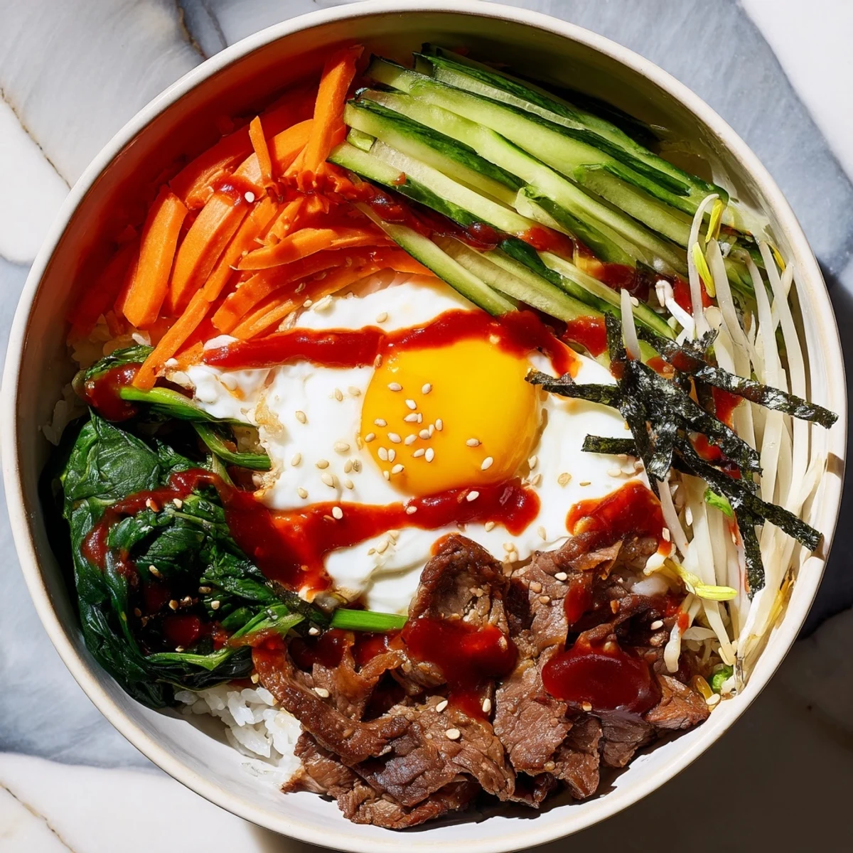 Golden fried egg atop Korean-inspired breakfast bowl with marinated beef, crisp vegetables, and gochujang drizzle over fluffy white rice