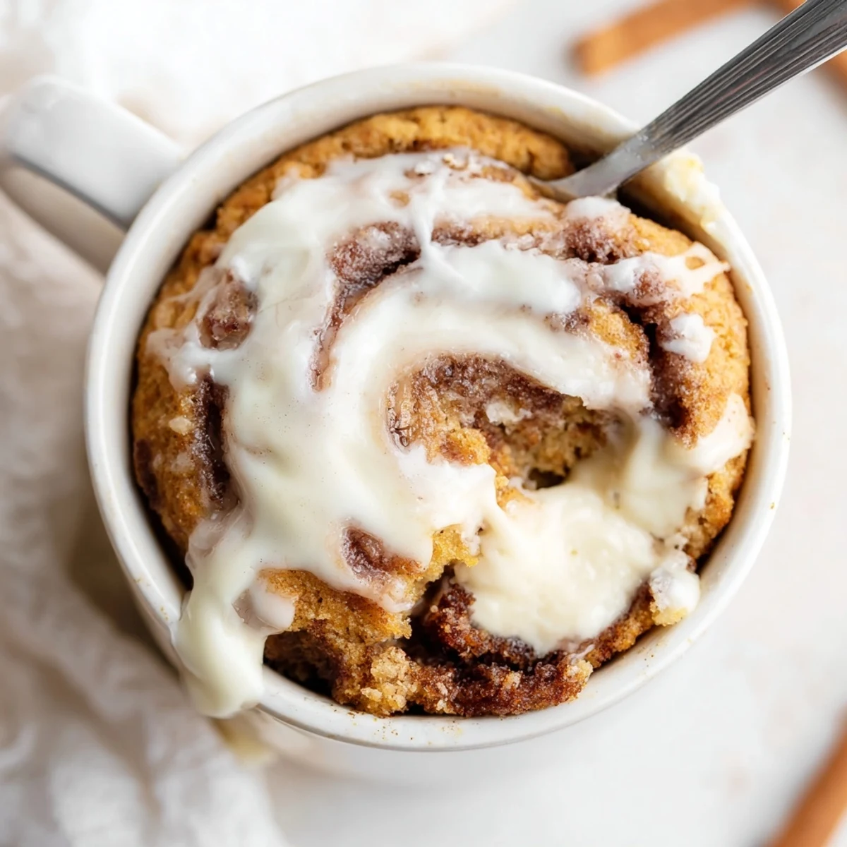 Fluffy single-serve cinnamon roll mug cake featuring protein-packed cottage cheese batter and cinnamon sugar swirl