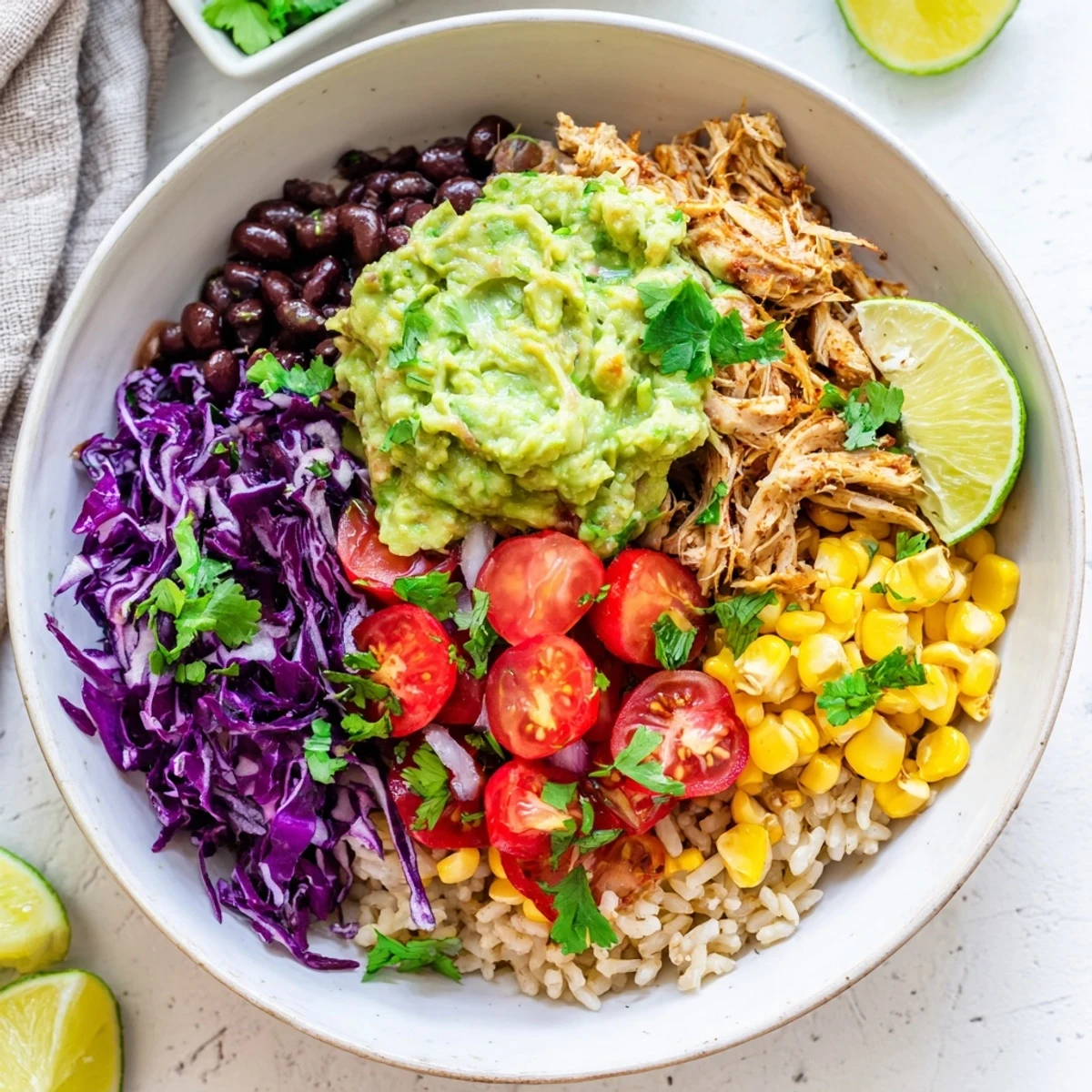 Colorful pulled chicken guacamole bowl with fresh tomatoes, beans, and shredded cabbage over rice