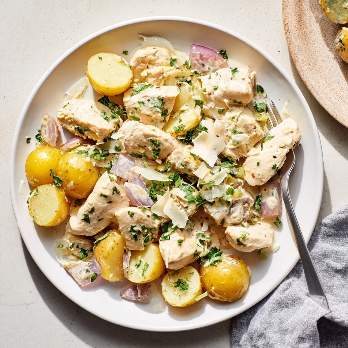 Tender chicken breasts nestled beside buttery potatoes in a savory garlic Parmesan glaze