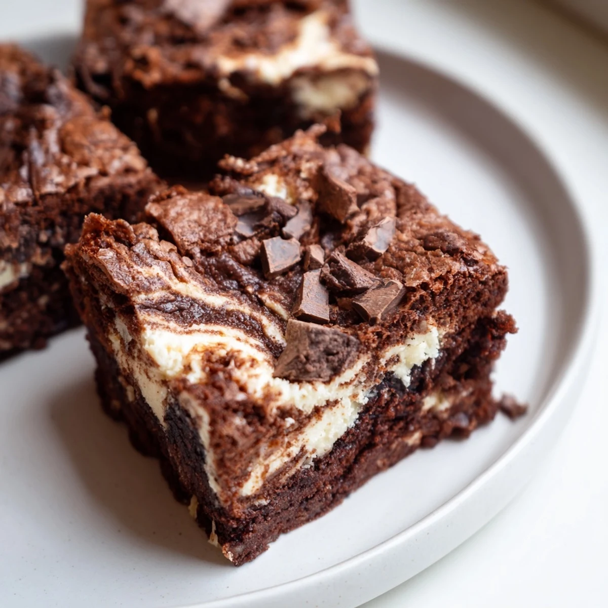 Baked tray of fudgy chocolate cheesecake swirled brownies with golden edges and creamy white swirls