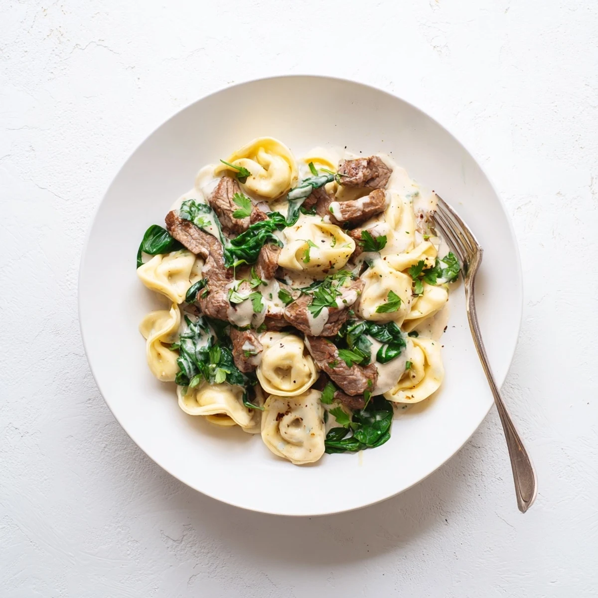 Plate of garlic steak tortellini garnished with parsley and extra parmesan cheese