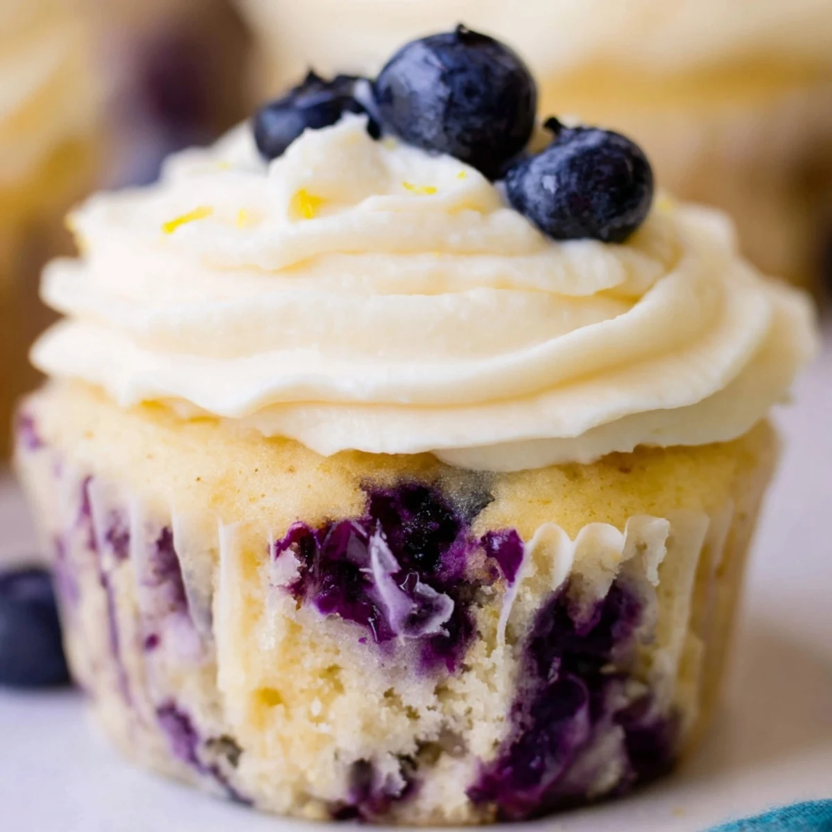 Freshly baked lemon blueberry cupcakes with zesty cream cheese frosting and whole blueberries on top