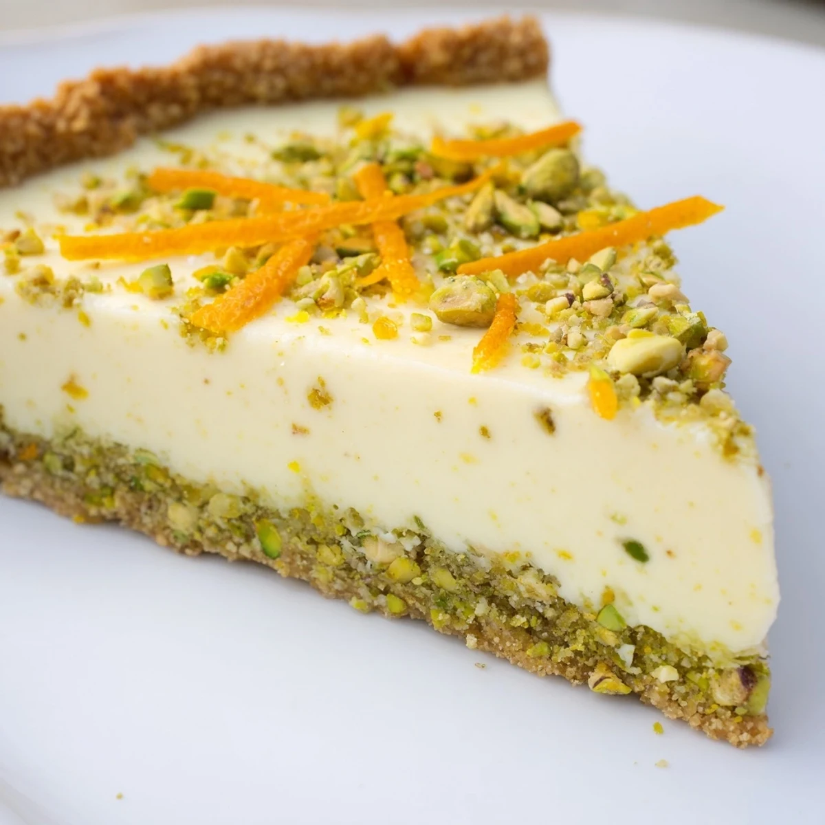 Golden orange cardamom tart with creamy citrus filling nestled in a crunchy pistachio crust