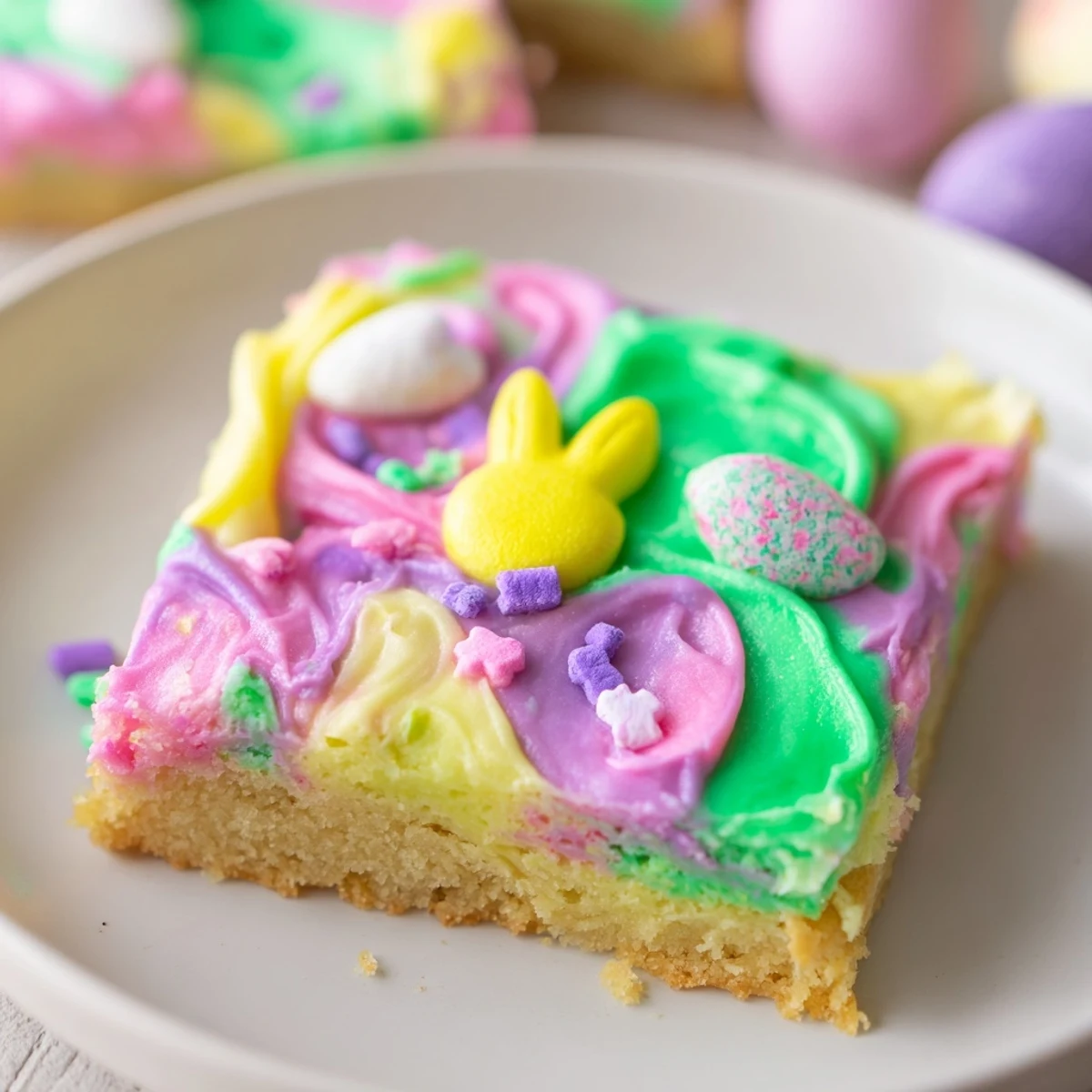 Soft Easter sugar cookie bars with swirled pastel frosting and colorful sprinkles on a white platter