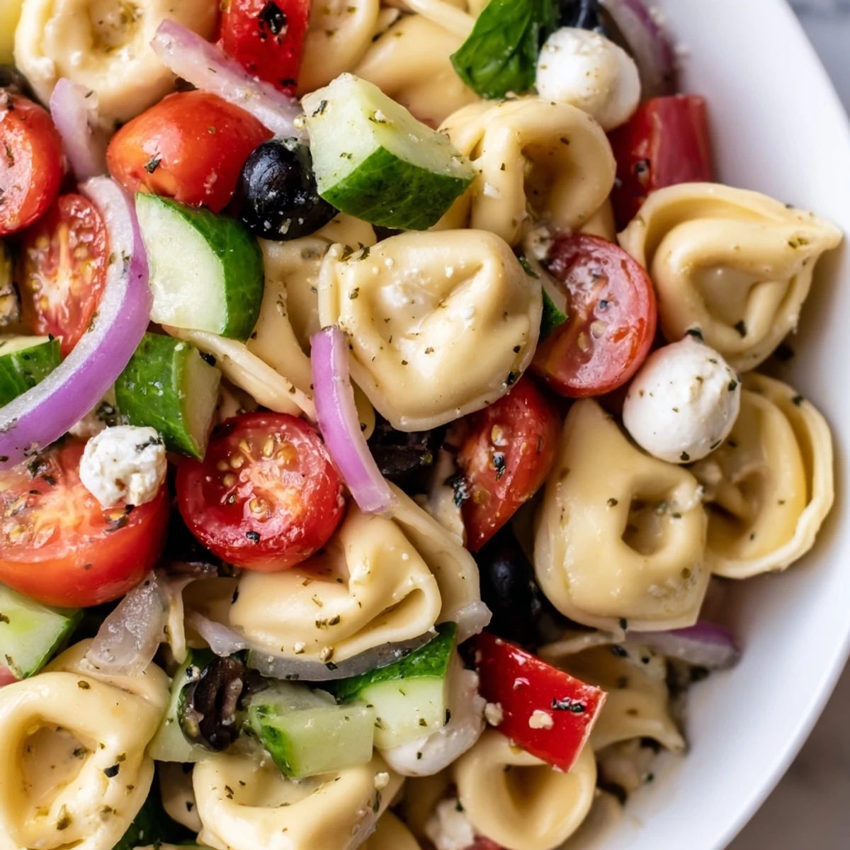 Colorful tortellini salad with cherry tomatoes, cucumbers, and mozzarella in zesty Italian dressing