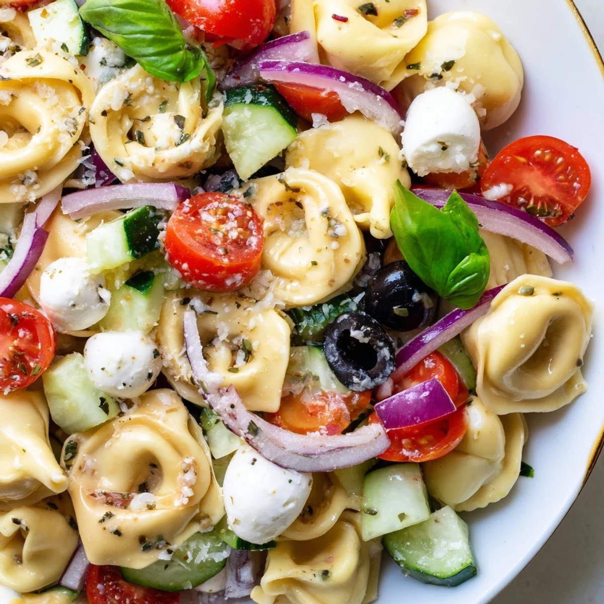 Creamy cheese tortellini salad tossed with crisp vegetables and fresh basil leaves