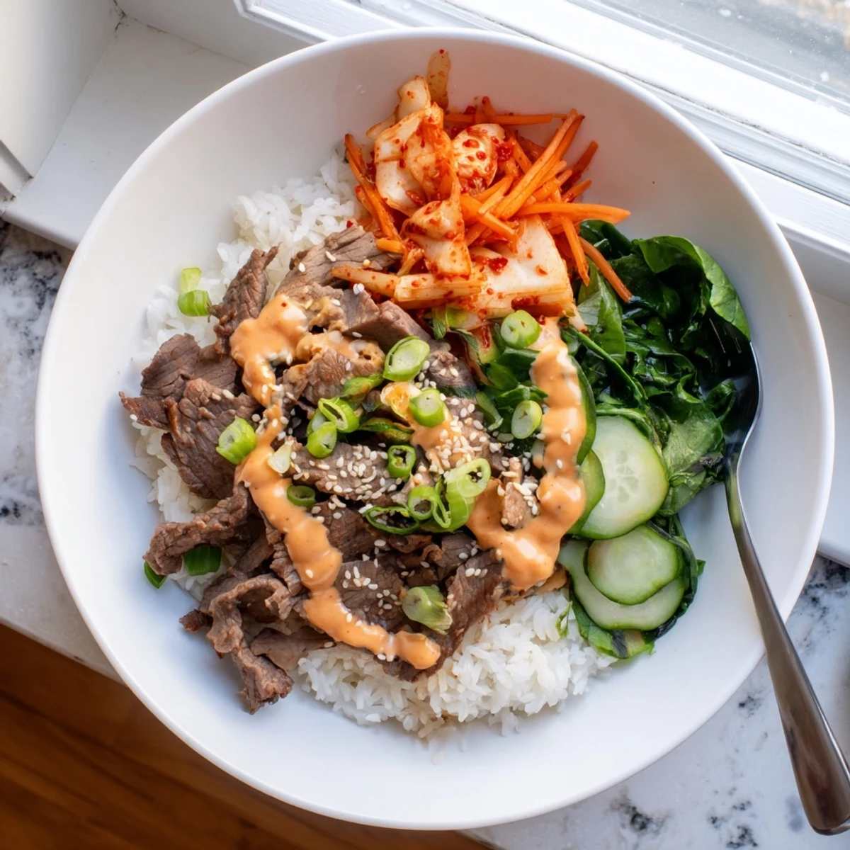 Caramelized marinated steak over fluffy jasmine rice with vibrant veggies and spicy cream sauce drizzled on top in these Korean BBQ steak rice bowls