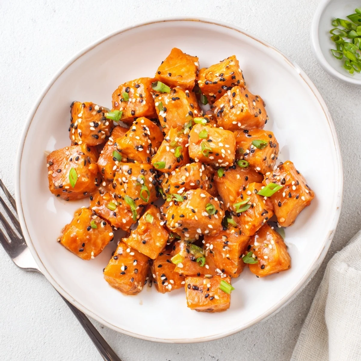 Plated Bang Bang Salmon Bites Recipe garnished with cilantro, sesame, creamy drizzle