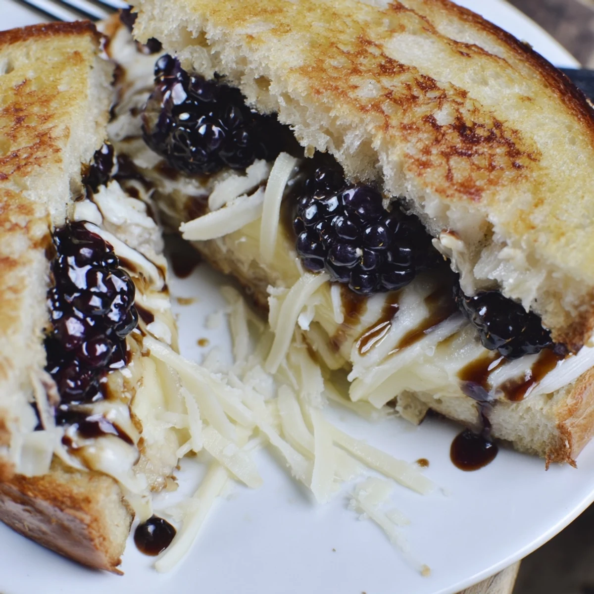 Cheesy Balsamic Blackberry Bliss Grilled Cheese halves on plate, juicy blackberries peeking