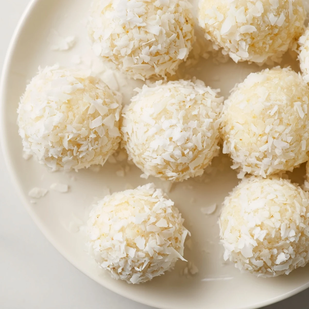 Golden no-bake Citrus Bliss Bits topped with fluffy white coconut on a white platter