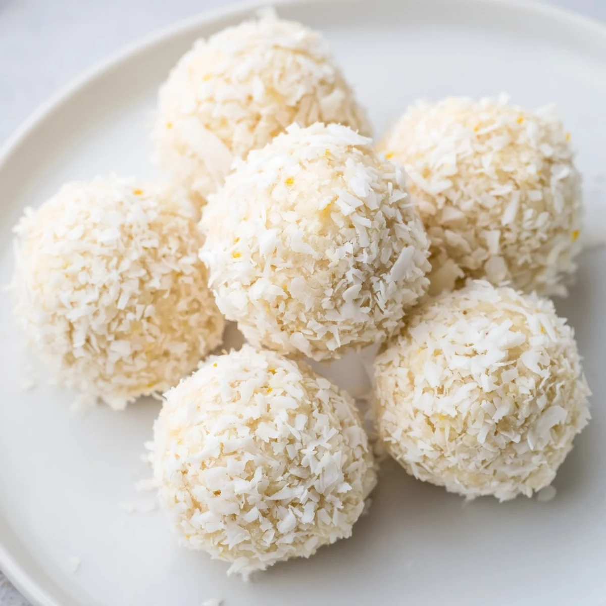 Freshly rolled citrus energy bites arranged on a wooden board with orange zest garnish