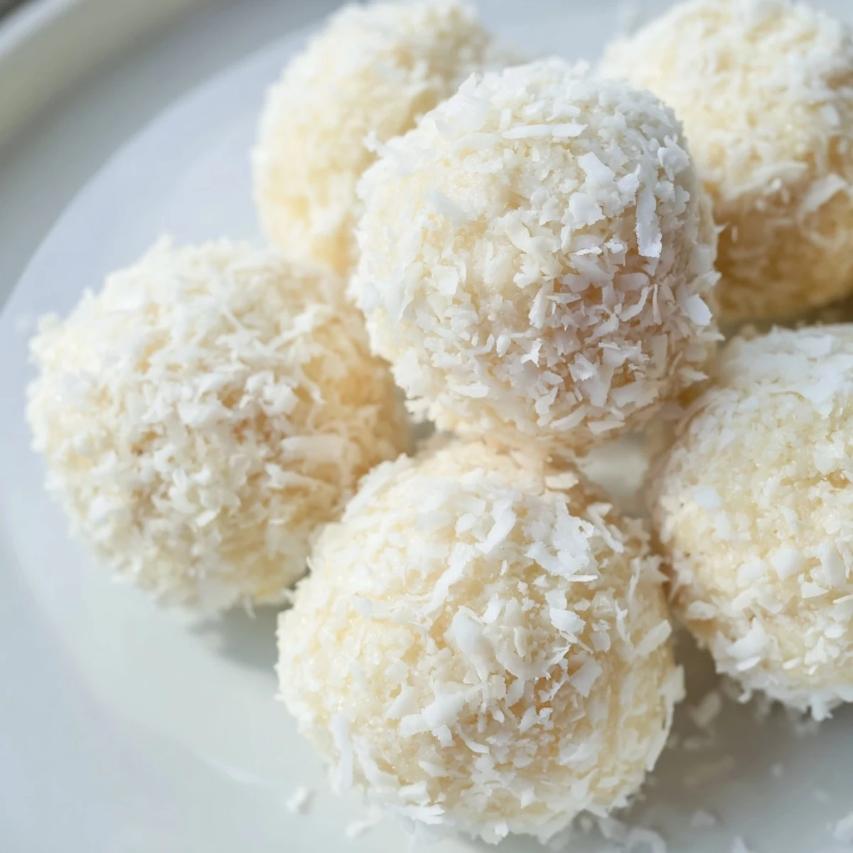 Bite-sized Citrus Bliss Bites coated in coconut on a parchment-lined serving tray