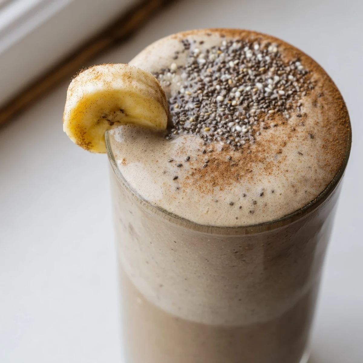 Thick caffeinated banana protein smoothie blended golden and served cold in a mason jar