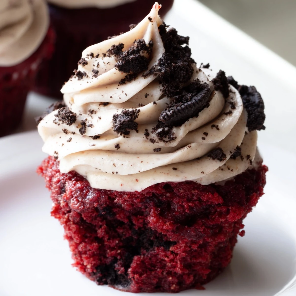 Rich red velvet Oreo cupcakes topped with creamy cookie-studded frosting on a rustic plate