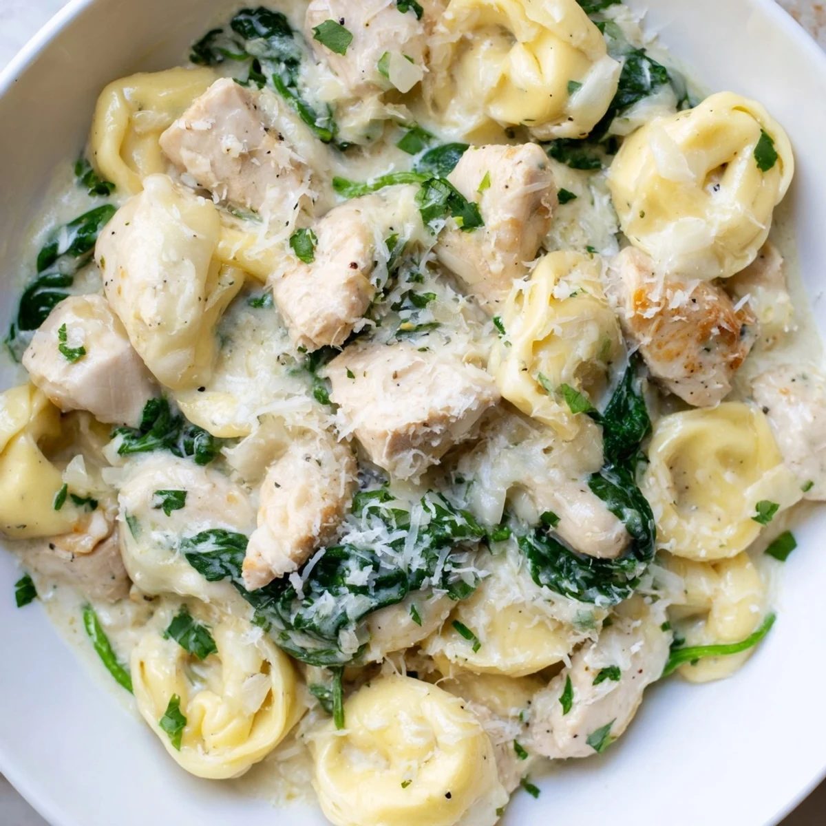 Creamy garlic chicken tortellini with spinach served in a white bowl