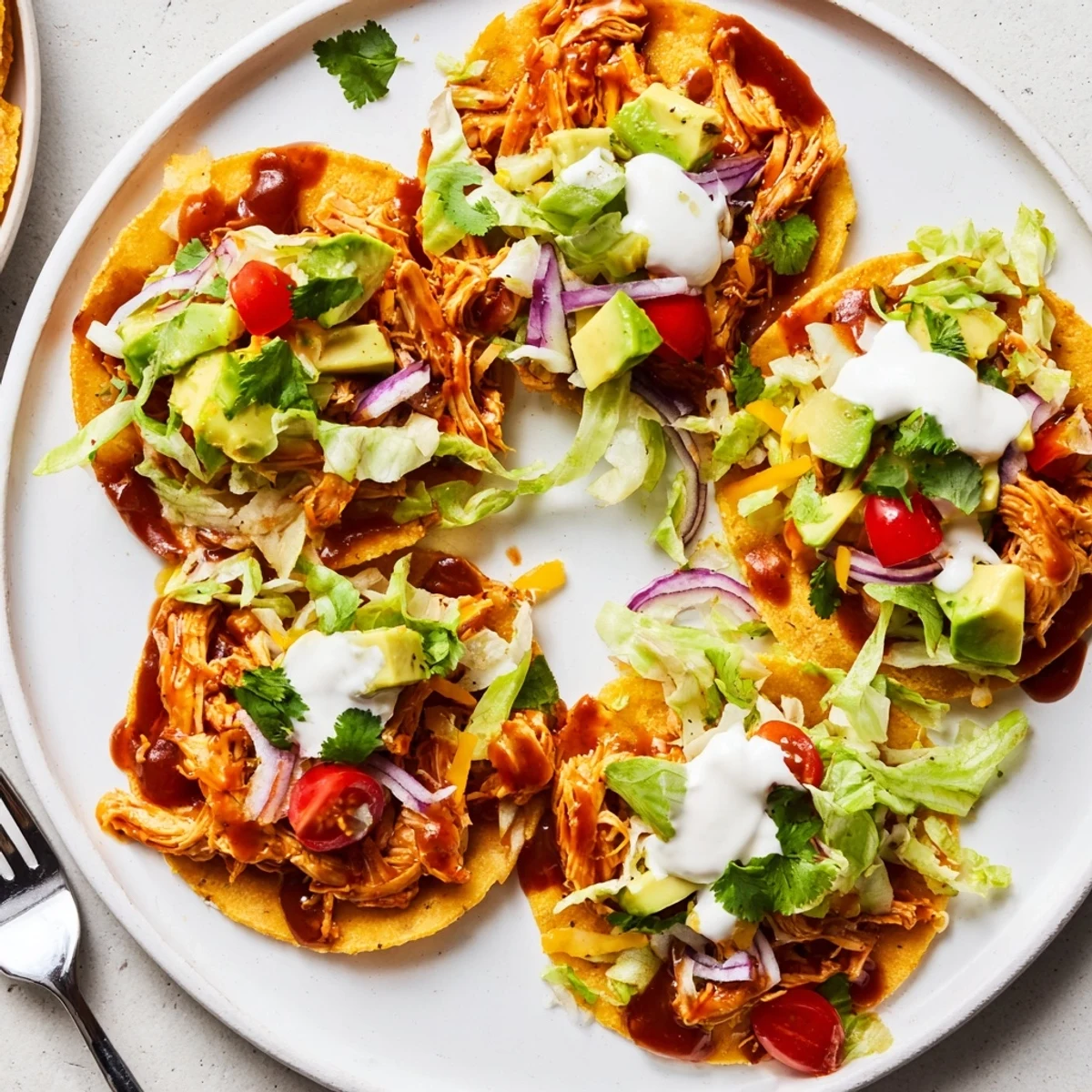 Crispy sweet smoky BBQ chicken tostadas piled high with fresh lettuce, tomato, and creamy avocado slices